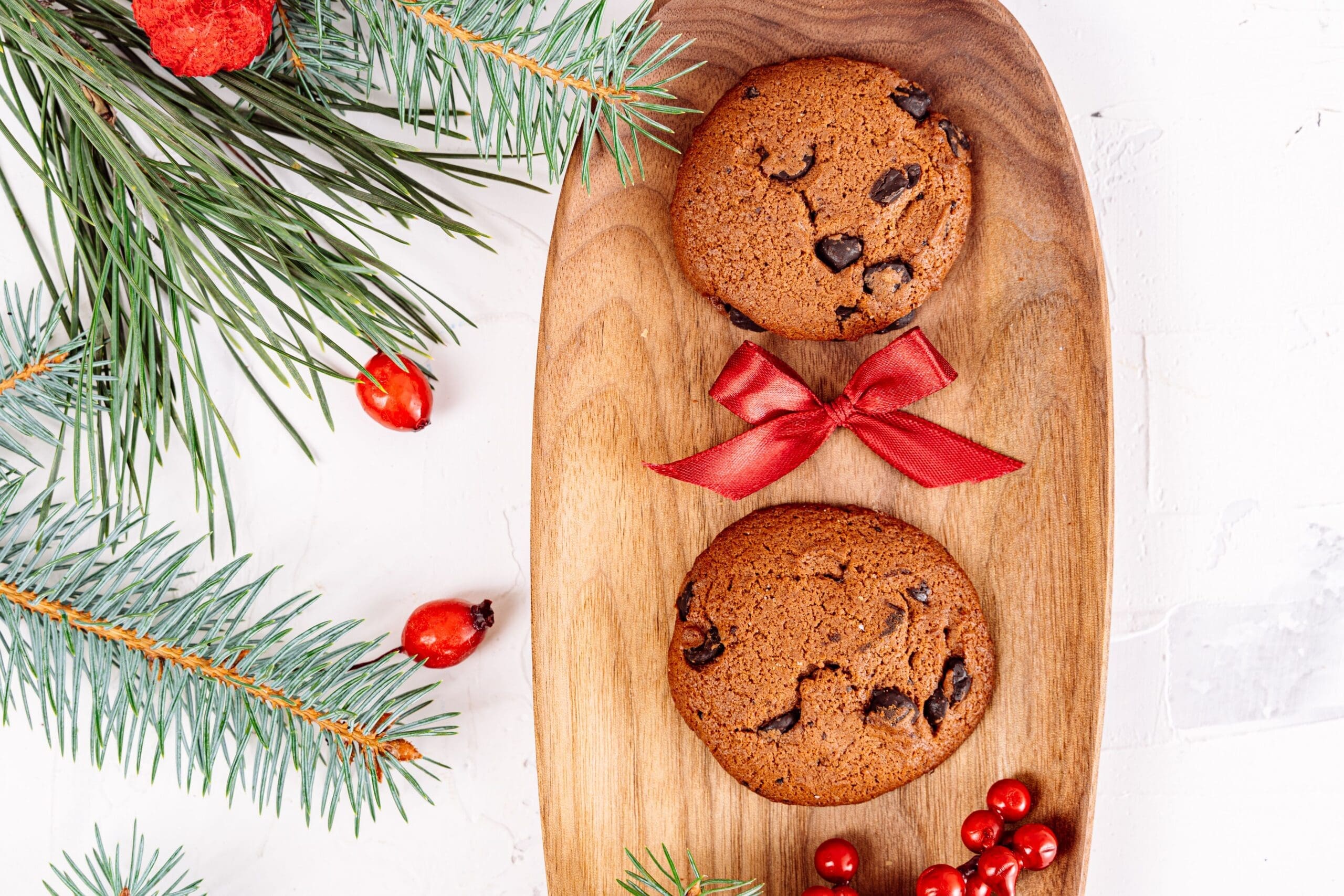 Chocolate cookies on a wooden board with a red ribbon and evergreen sprig