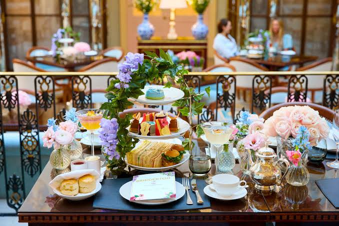 Elegant afternoon tea table with tiered sandwiches, scones and pastel flowers