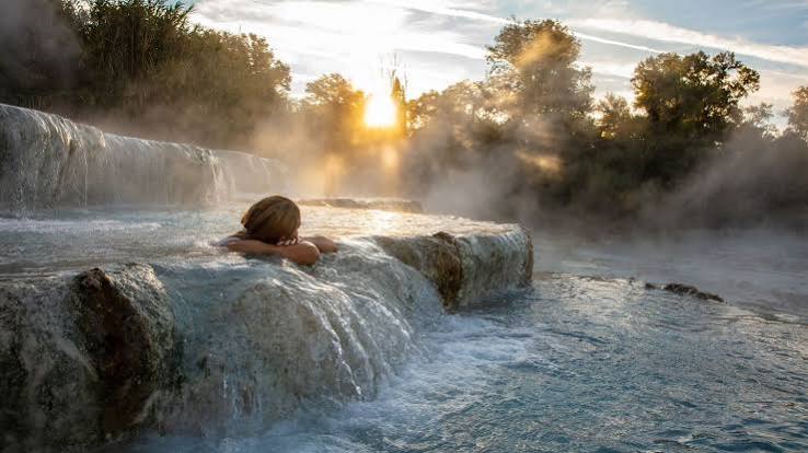 Woman relaxing in natural hot springs at sunrise